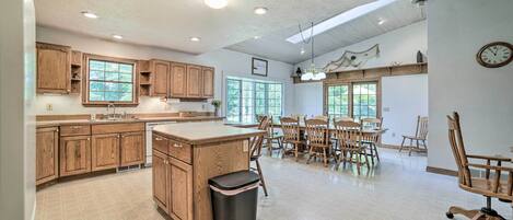 A spacious kitchen with wooden cabinets, a large island, and a dining area with wooden chairs and a table.