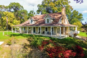 A two-story house with a porch, a chimney, and a flagpole.