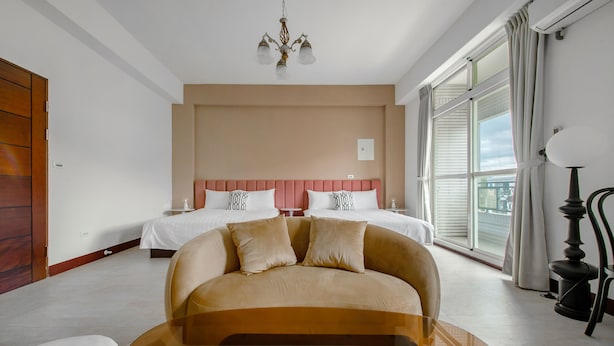 Hotellihuone, jossa on suuri sänky, sohva, kattokruunu ja näkymä ulos.