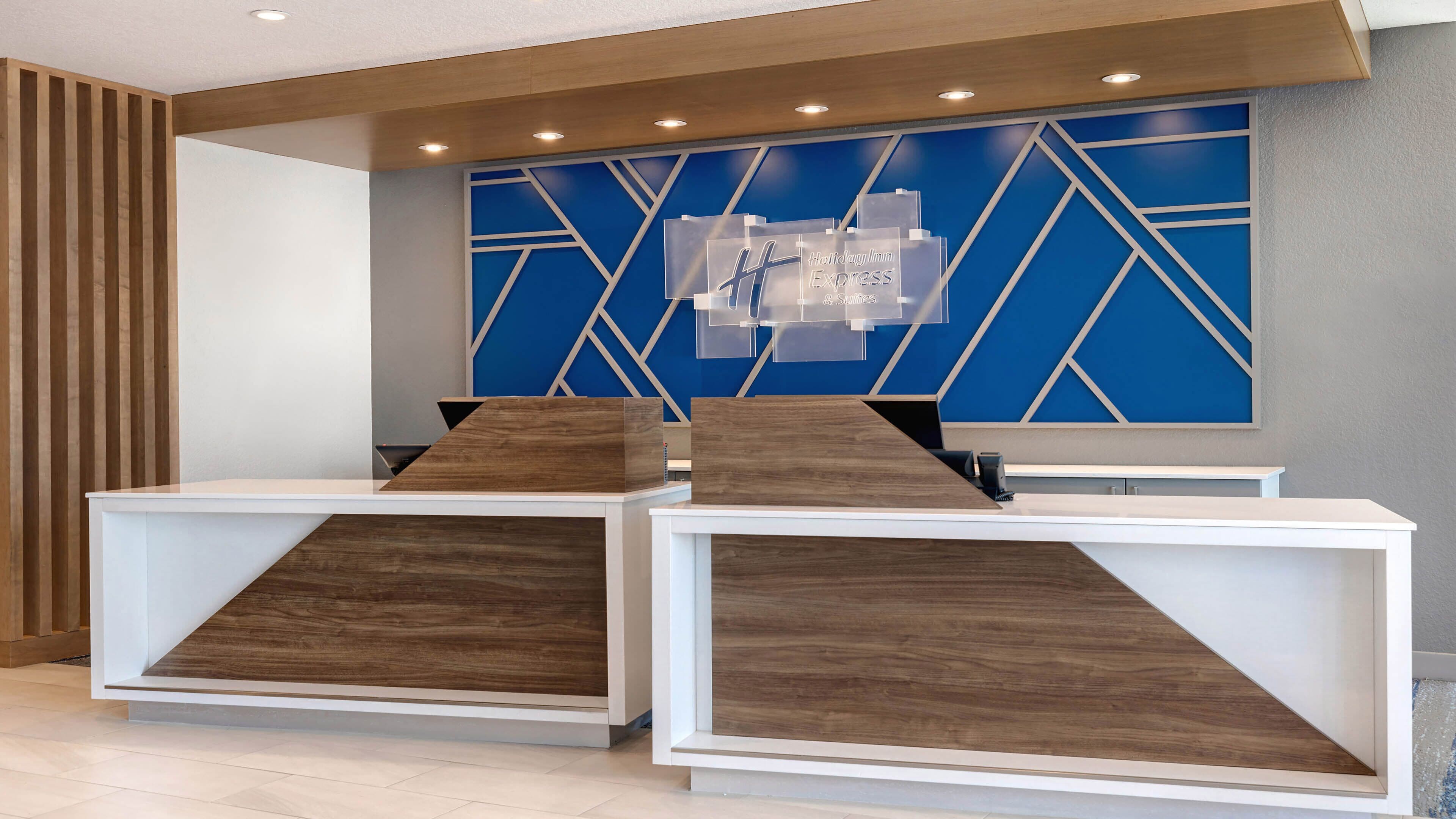 A reception desk with a modern design, featuring a blue geometric wall and wooden accents.