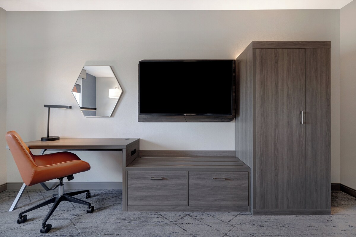 A modern room with a desk, chair, TV, and wardrobe.