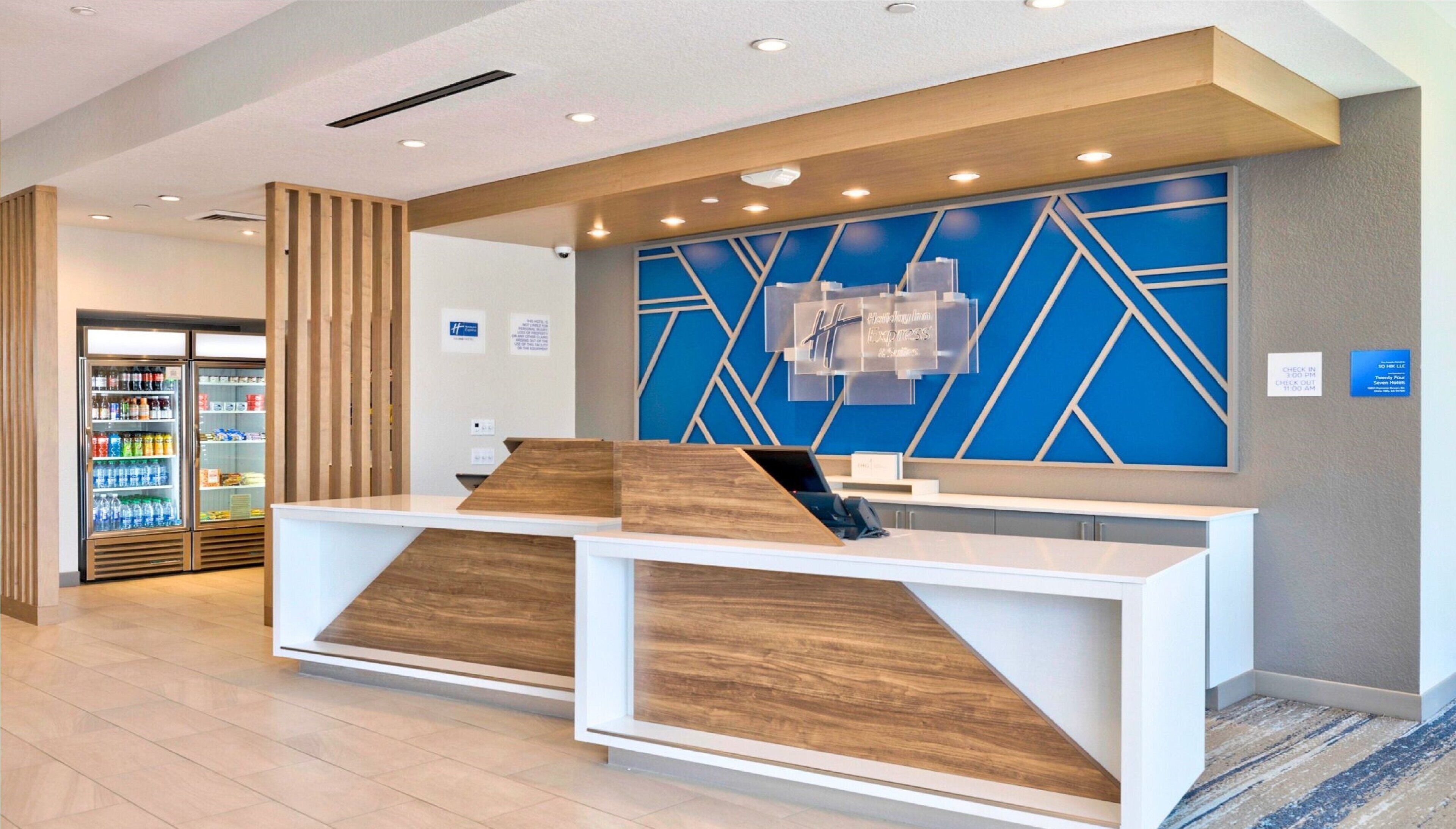 Zona de recepción con diseño moderno, que incluye mostrador de recepción, panel informativo en la pared y dispensador de agua.