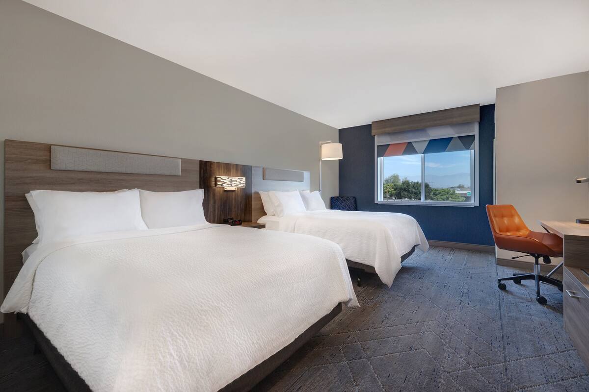 Una habitación de hotel con dos camas, un escritorio y una silla.