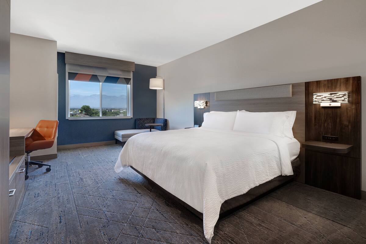 Una habitación de hotel moderna con una cama grande, un escritorio y una silla.