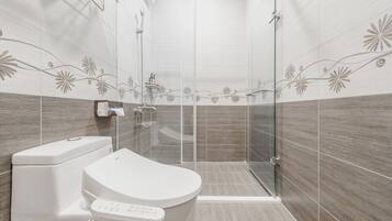 A modern bathroom with a toilet, a glass shower enclosure, and decorative wall tiles.