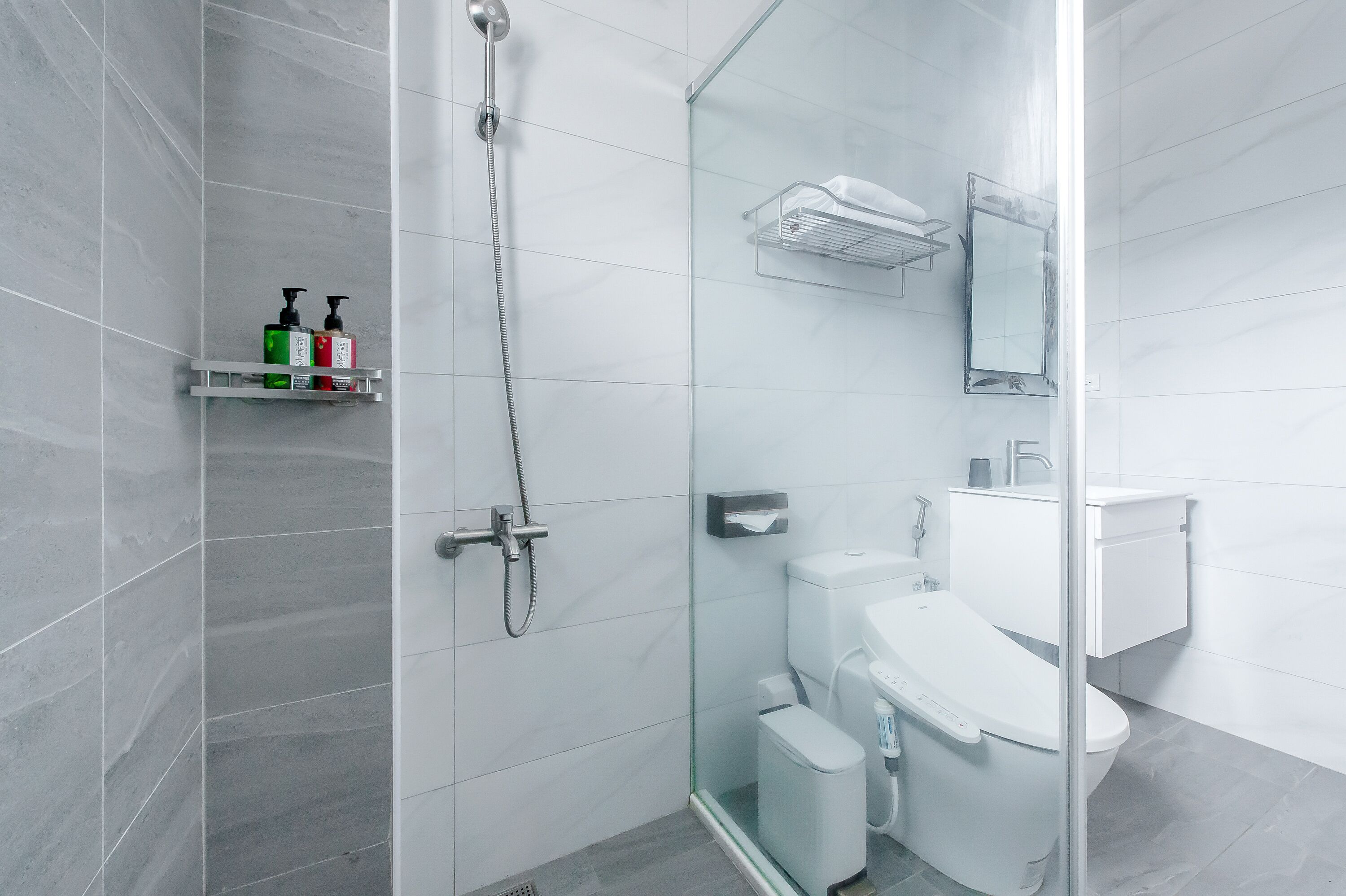 Un baño moderno con cabina de ducha de vidrio, inodoro blanco y lavamanos de vidrio.