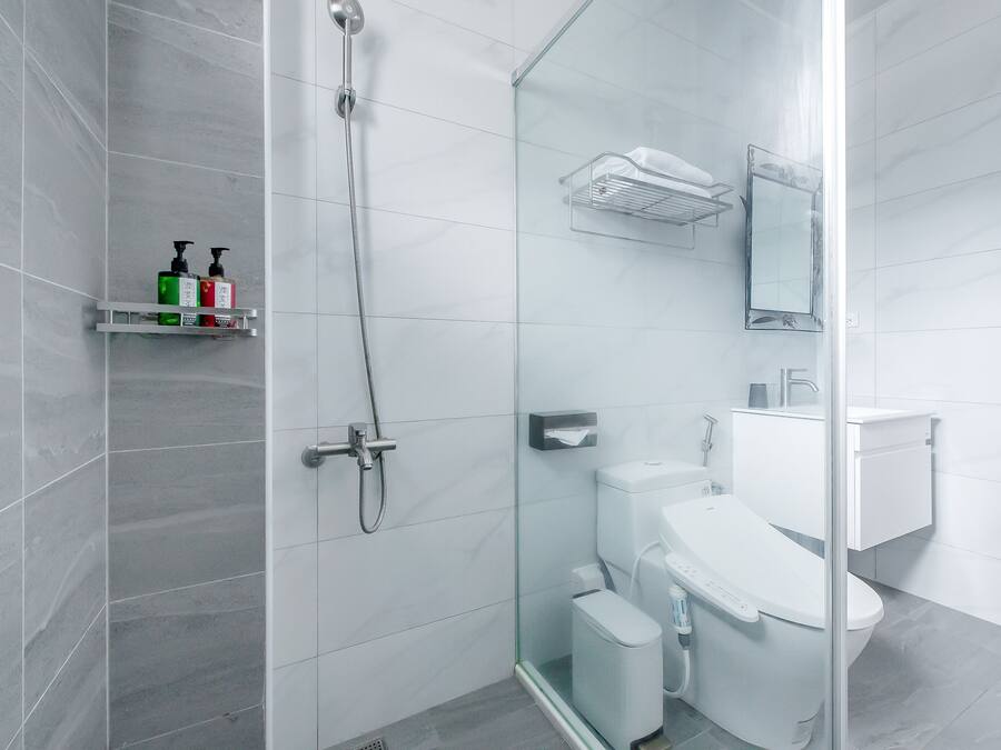 Un baño moderno con cabina de ducha de vidrio, inodoro blanco y lavamanos de vidrio.