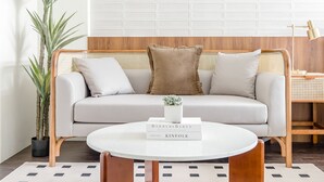 Ein modernes Wohnzimmer mit einem hellen Sofa, einem runden Couchtisch und einem Topf mit Pflanze.