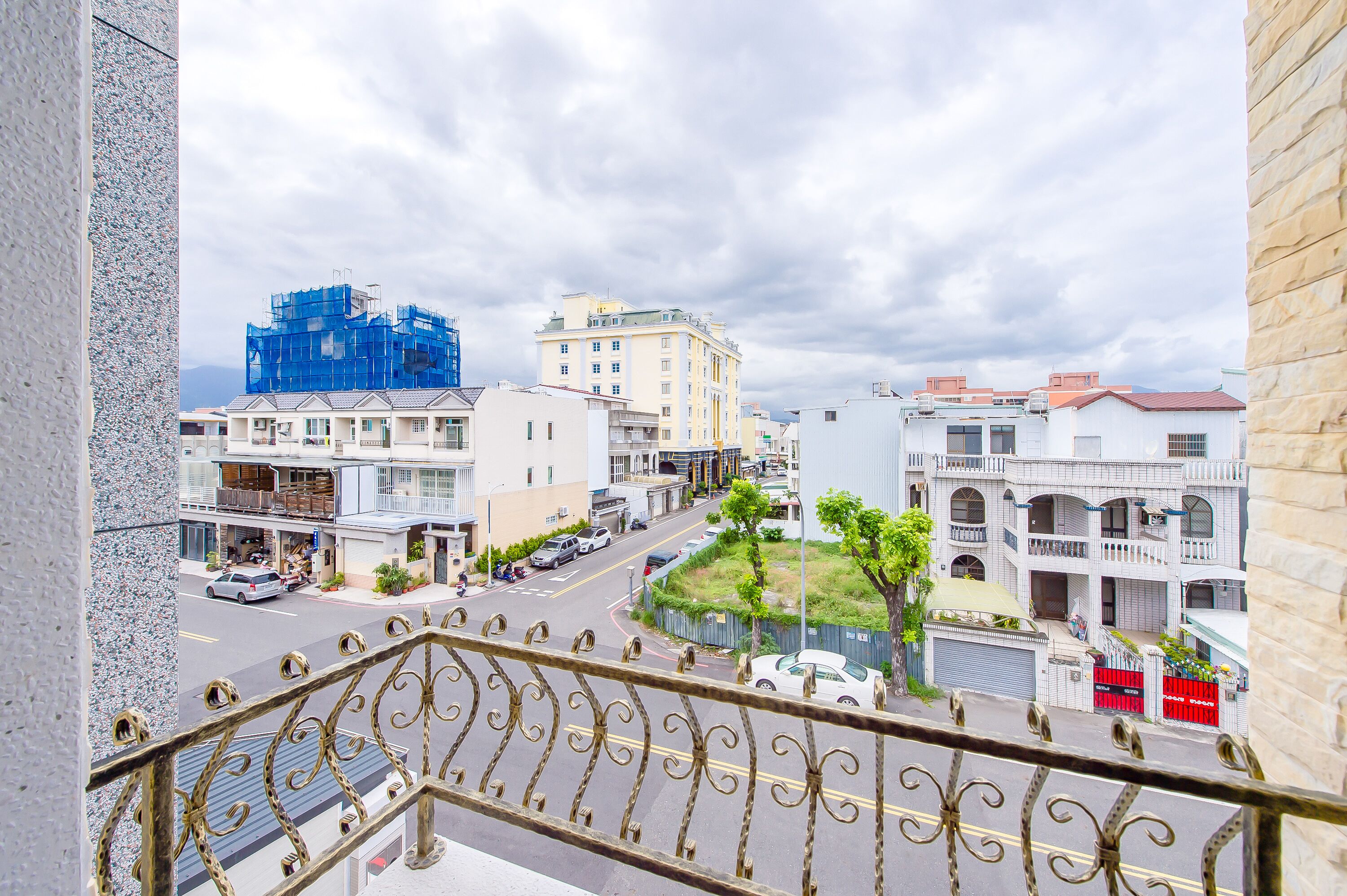 A balcony with a view of a street, buildings, and a construction site.