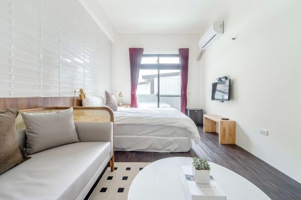 Une chambre d’hôtel moderne équipée d’un canapé, d’un lit, d’une petite table et d’un téléviseur.