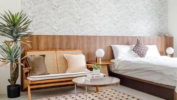 Un dormitorio moderno con cabecera de madera, un sofá de ratán, una mesa de centro redonda y una planta grande en maceta.