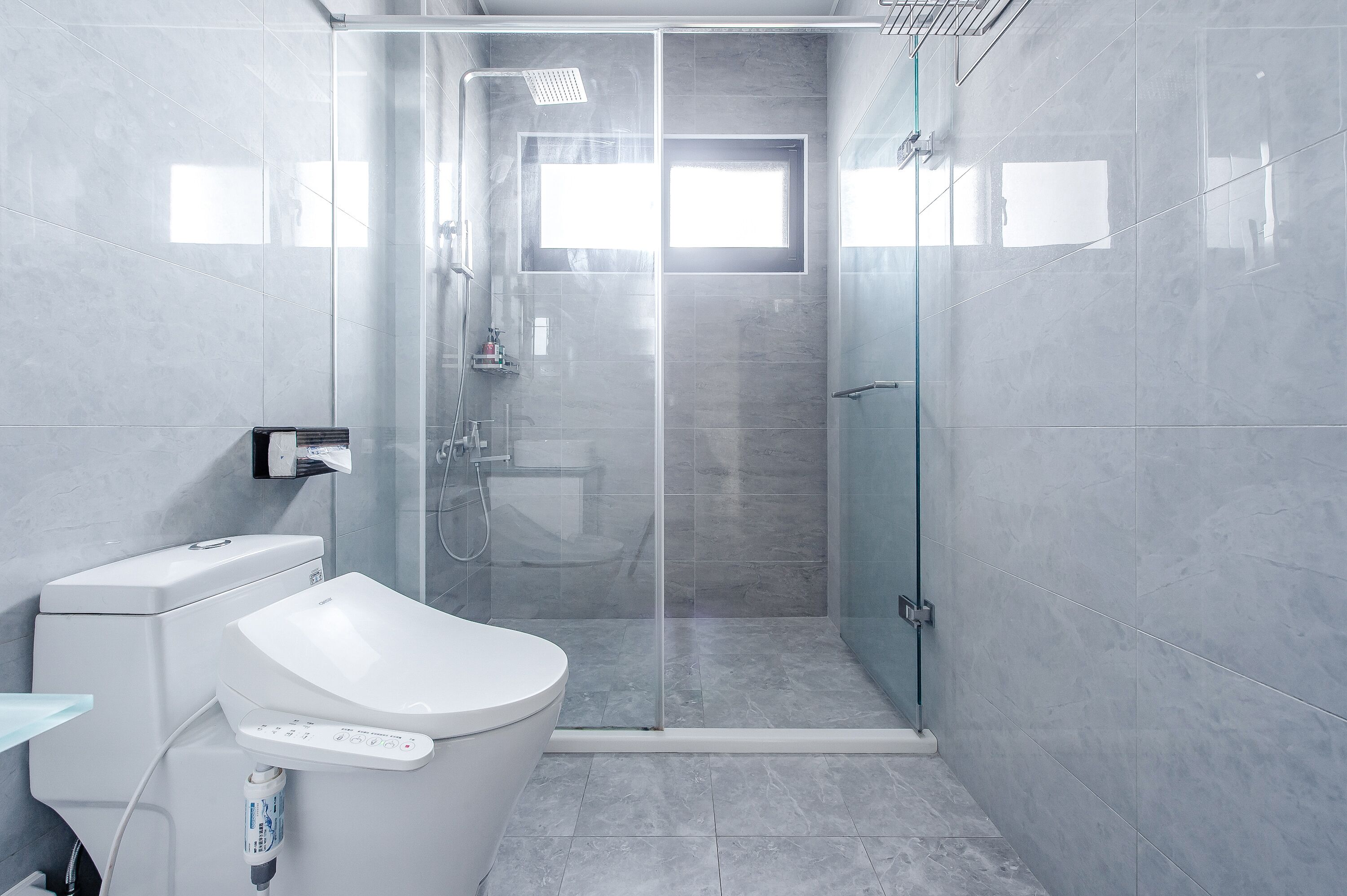 Un baño moderno con inodoro, bidé y zona de ducha con mampara de vidrio.