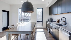 Een moderne keuken met een groot eiland, roestvrijstalen apparatuur en een hanglamp.