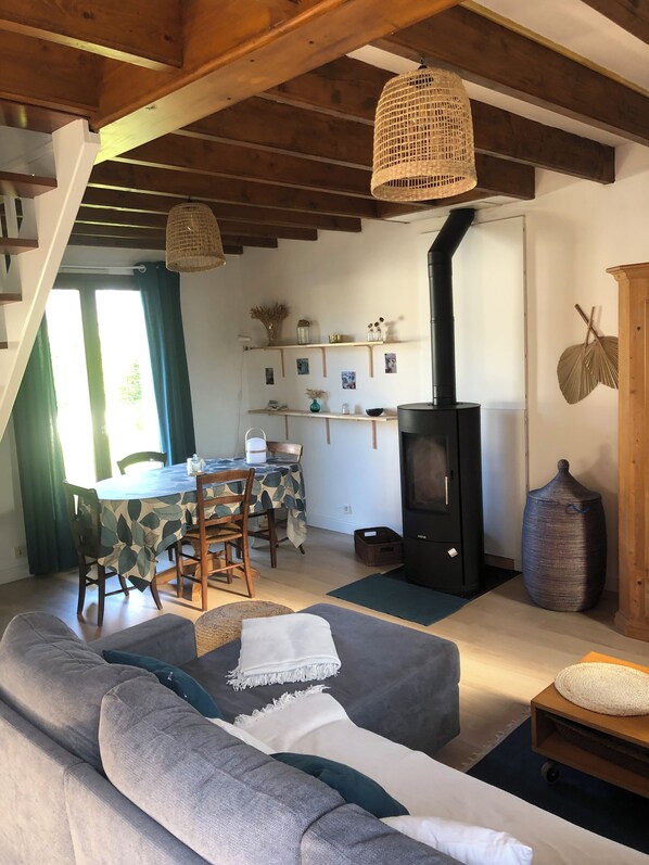 A cozy living room with a sofa, a dining table, and a black wood-burning stove.