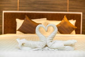 A bed with a heart-shaped towel arrangement and decorative pillows.