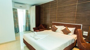 A modern hotel room with a large bed, brown headboard, and a wooden accent wall. - Royal Raj Hotel & Condominium (Rajshahi)