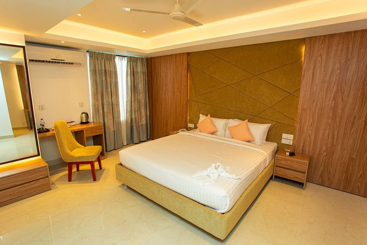 A modern hotel room with a large bed, a desk, and a chair.