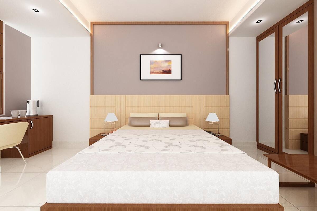 A modern hotel bedroom with a large bed, bedside lamps, a framed picture on the wall, and a wardrobe.