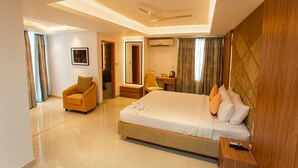 A modern hotel room with a large bed, a desk, a chair, and a bathroom visible through an open door. - Royal Raj Hotel & Condominium (Rajshahi)