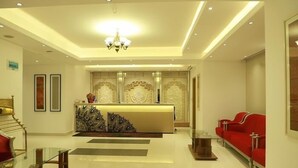 A hotel lobby with a reception desk, red sofas, a chandelier, and a staircase. - Royal Raj Hotel & Condominium (Rajshahi)