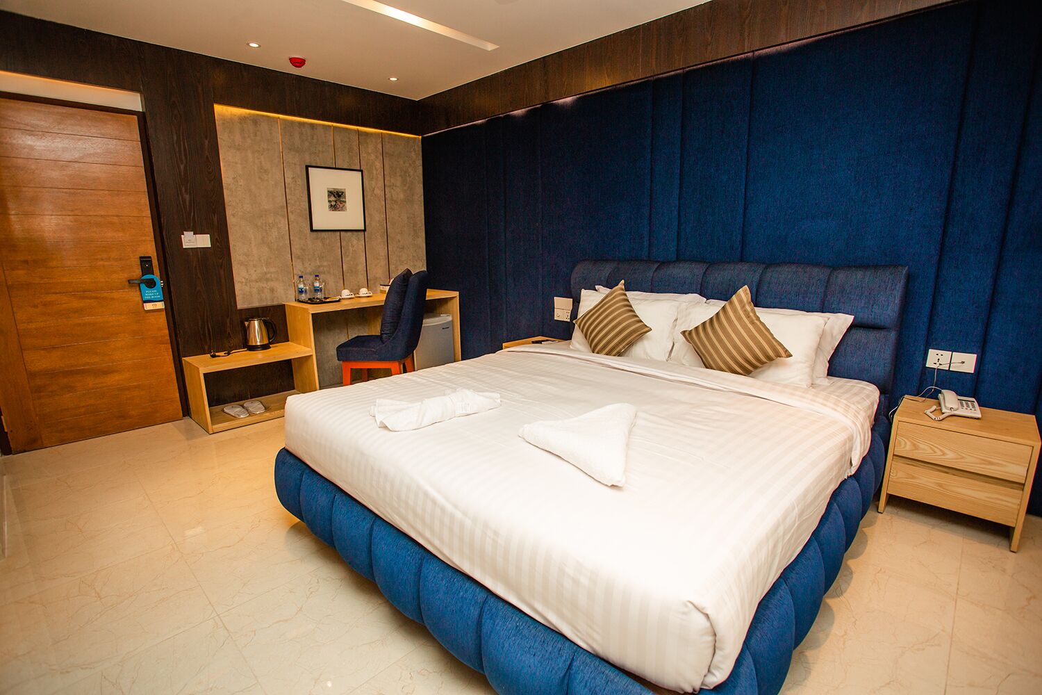 A hotel room with a large bed, a desk, a chair, and a small table.