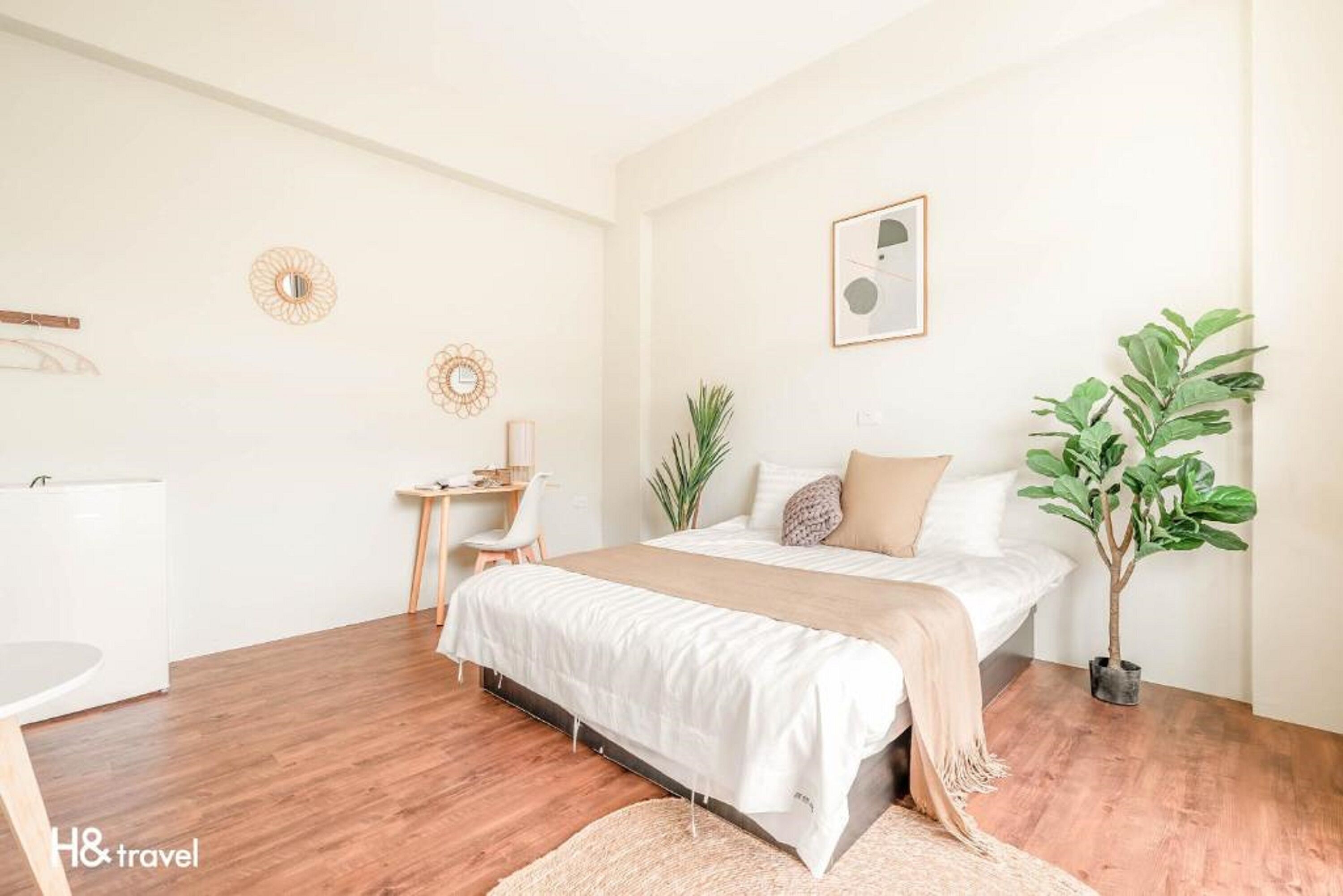 A minimalist bedroom with a bed, bedside table, chair, and a potted plant.