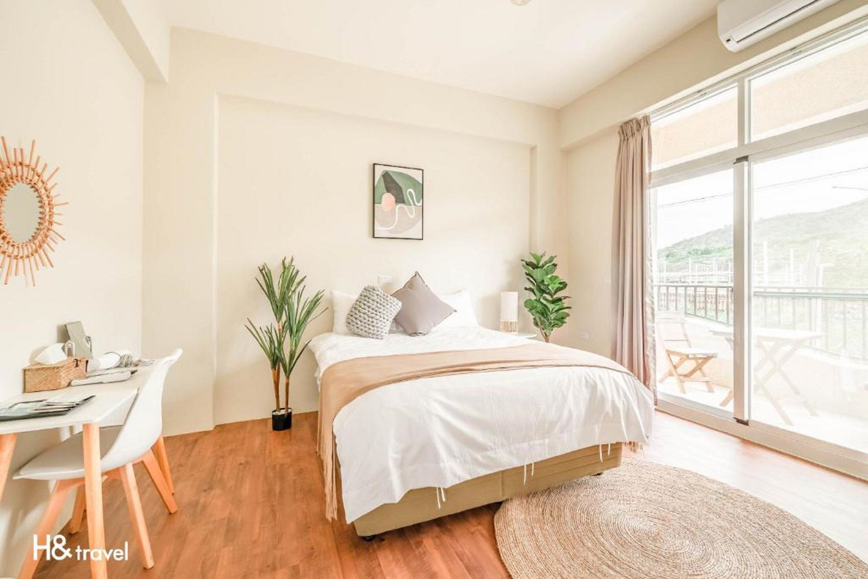 Une chambre à coucher avec un lit, des tables de chevet, un bureau et une grande fenêtre.