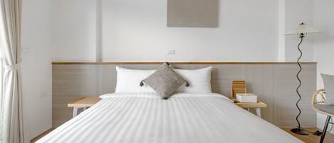 A neatly made bed with a striped bedspread, a single pillow, and a bedside table with a lamp.