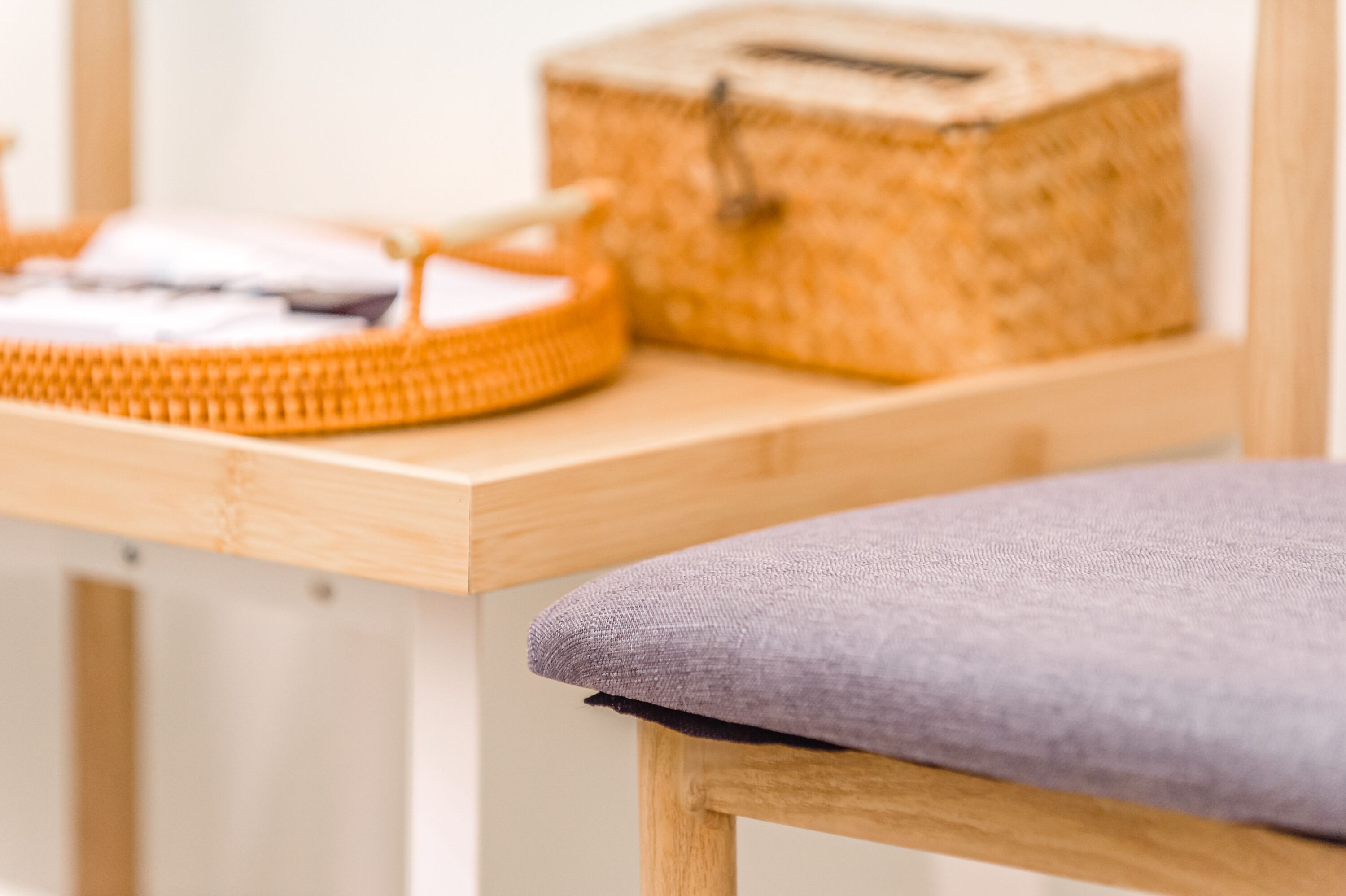 A wooden table with a wicker basket and a woven tray.