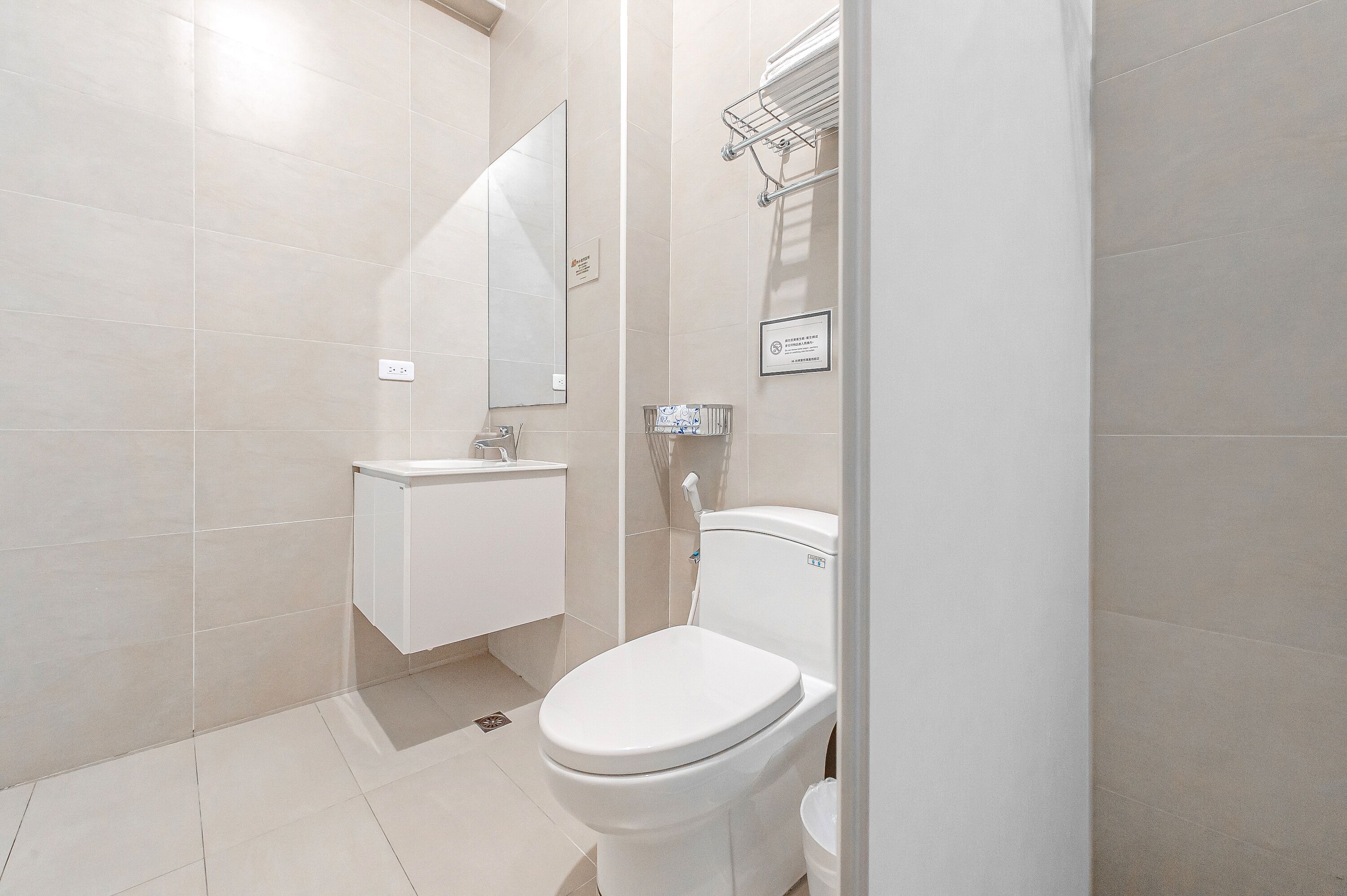 A modern bathroom with a toilet, sink, and mirror.