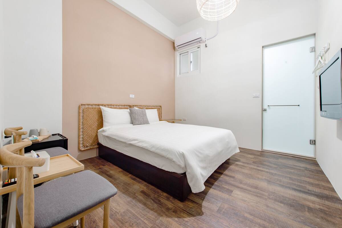 A neatly arranged bedroom with a bed, bedside table, chair, and a small table with a tray.