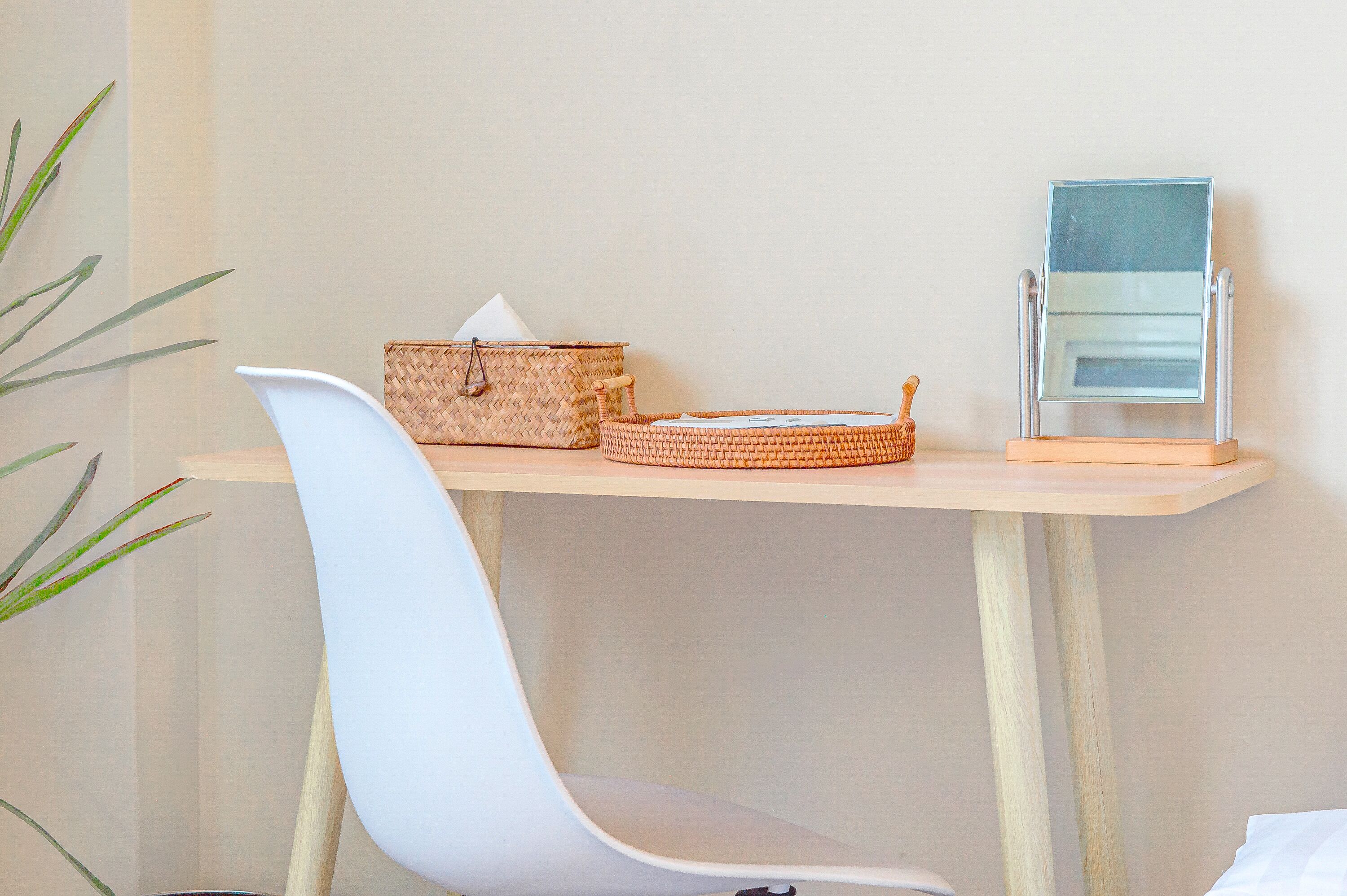 A small, clean room with a white chair, a wooden table, and a woven basket.