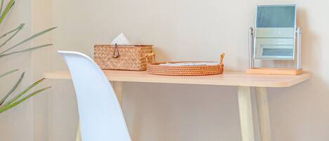 A small, clean room with a white chair, a wooden table, and a woven basket.