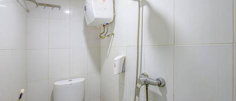 Un baño con inodoro, cabezal de ducha manual y secamanos de pared.