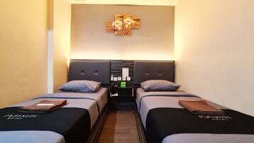 Une chambre d’hôtel avec deux lits simples, une table de chevet avec une lampe et une œuvre d’art accrochée au mur.