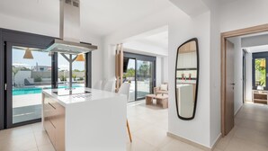 A modern kitchen with a central island, large windows, and a view of a swimming pool.