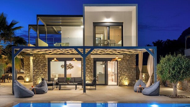 A modern house with a pool, outdoor seating, and a stone facade.
