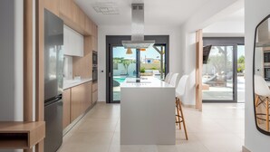 A modern kitchen with a central island, wooden cabinets, and a view of the outdoors.