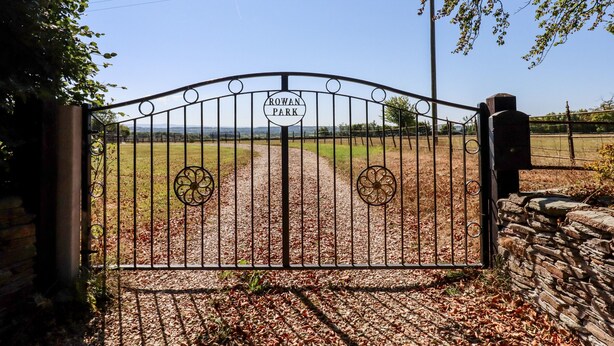 Ein Metalltor mit einem Schild, auf dem 'Rowan Park' steht, führt zu einer grünen Wiese.