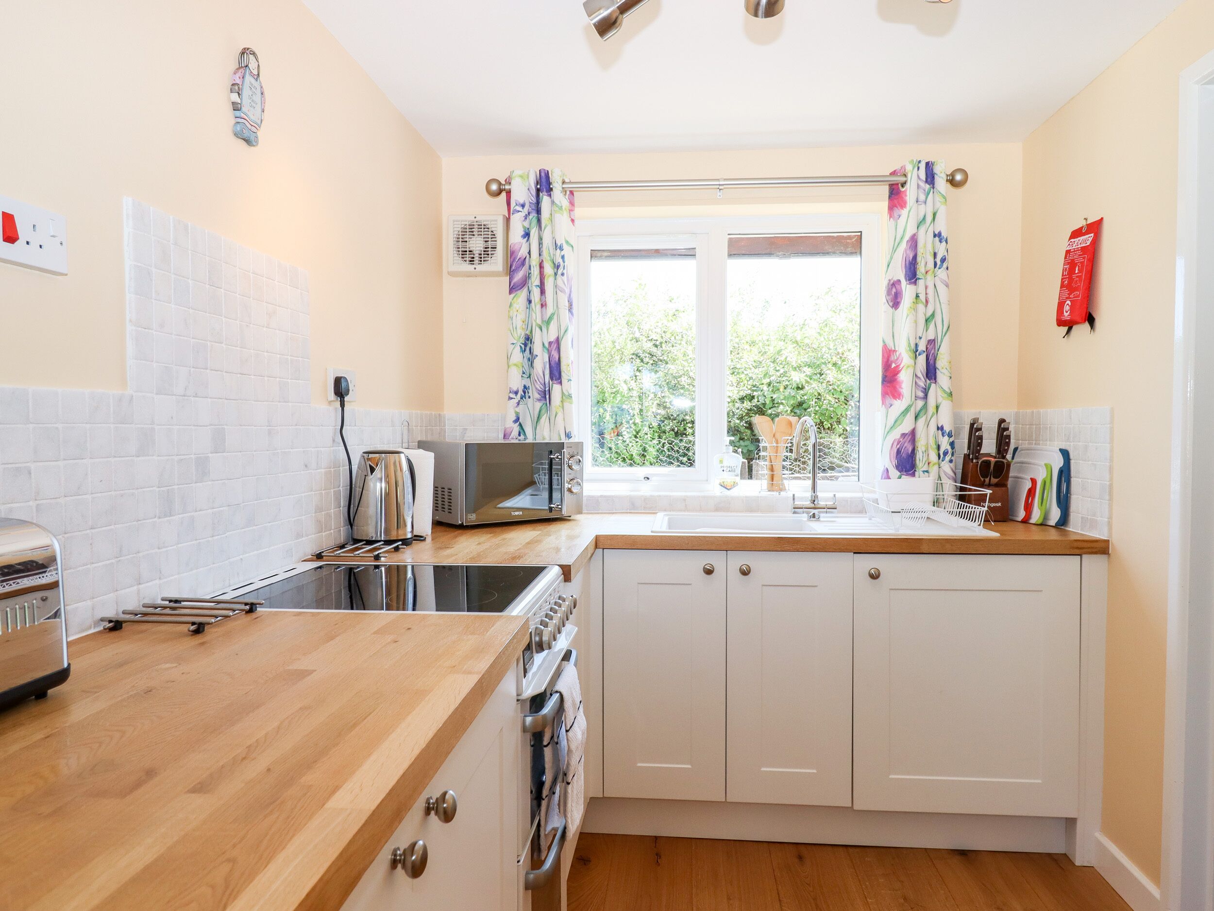 A modern kitchen with a wooden countertop, a built-in oven, a microwave, and a sink.