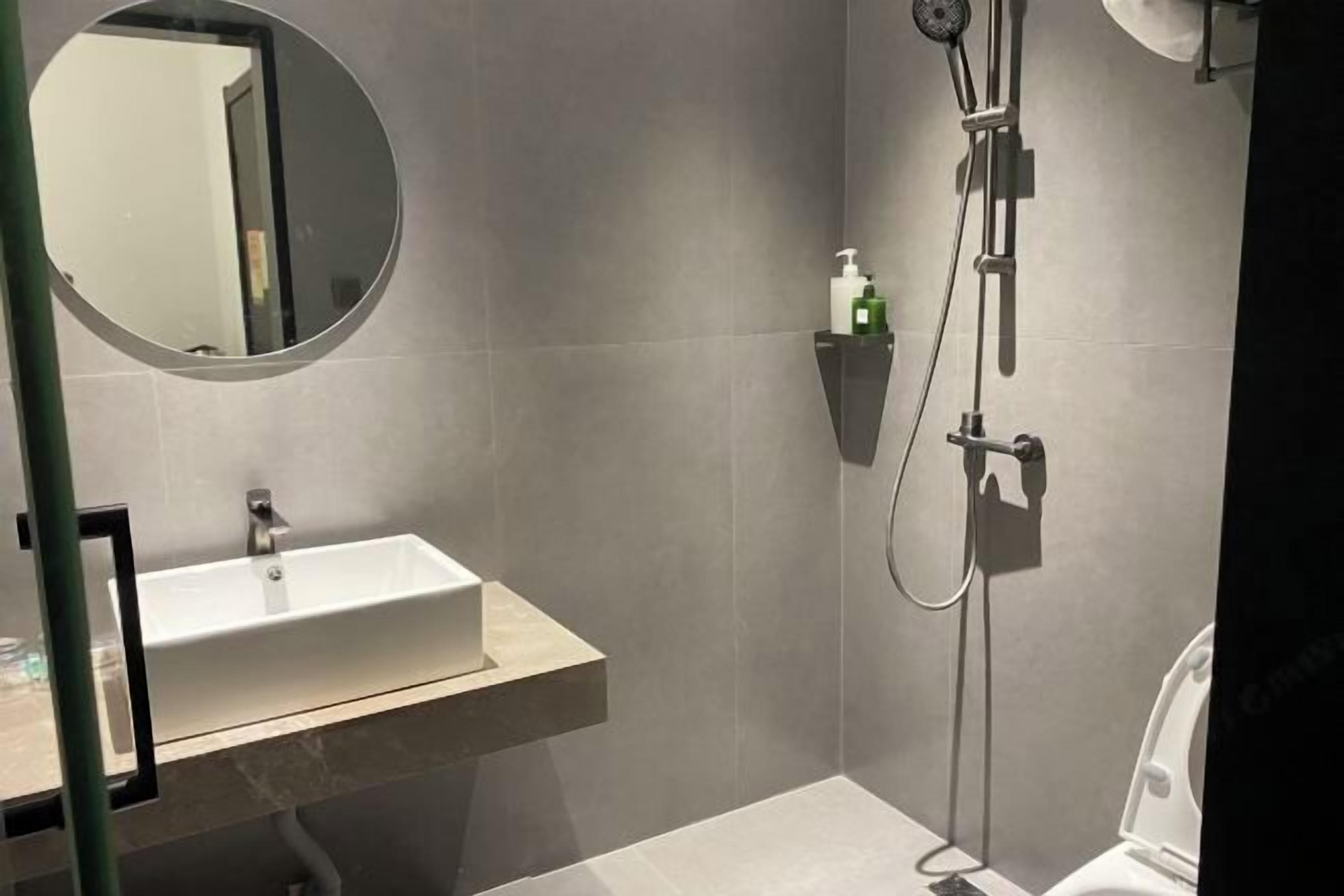 A modern bathroom with a rectangular sink, a handheld showerhead, and a toilet.