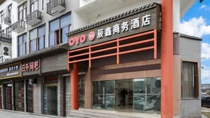 Un hotel con un llamativo letrero 'OYO', que presenta una fachada moderna con grandes ventanas de vidrio y una combinación de colores rojo y gris.