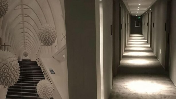 Un pasillo largo y estrecho con una escalera a la izquierda que lleva a una plataforma.