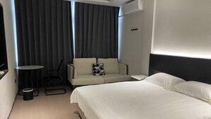Una habitación de hotel con una cama, un sofá, una mesita y una silla.