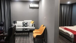Una habitación de hotel moderna con sofá, dos sillones, escritorio y cama.