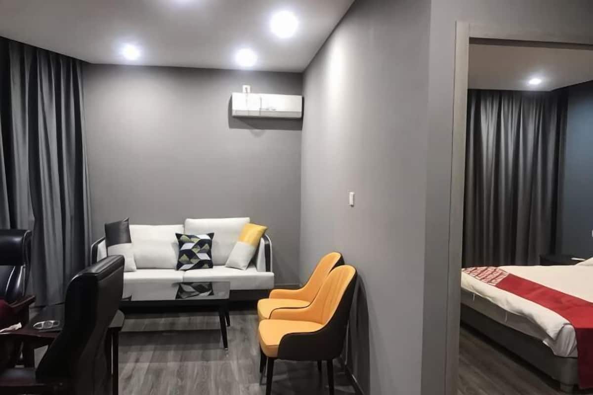 A modern hotel room with a sofa, two chairs, a desk, and a bed.