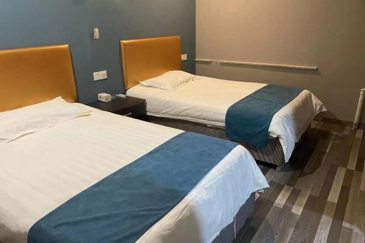 Two single beds with headboards, a nightstand, and a wall-mounted handrail.