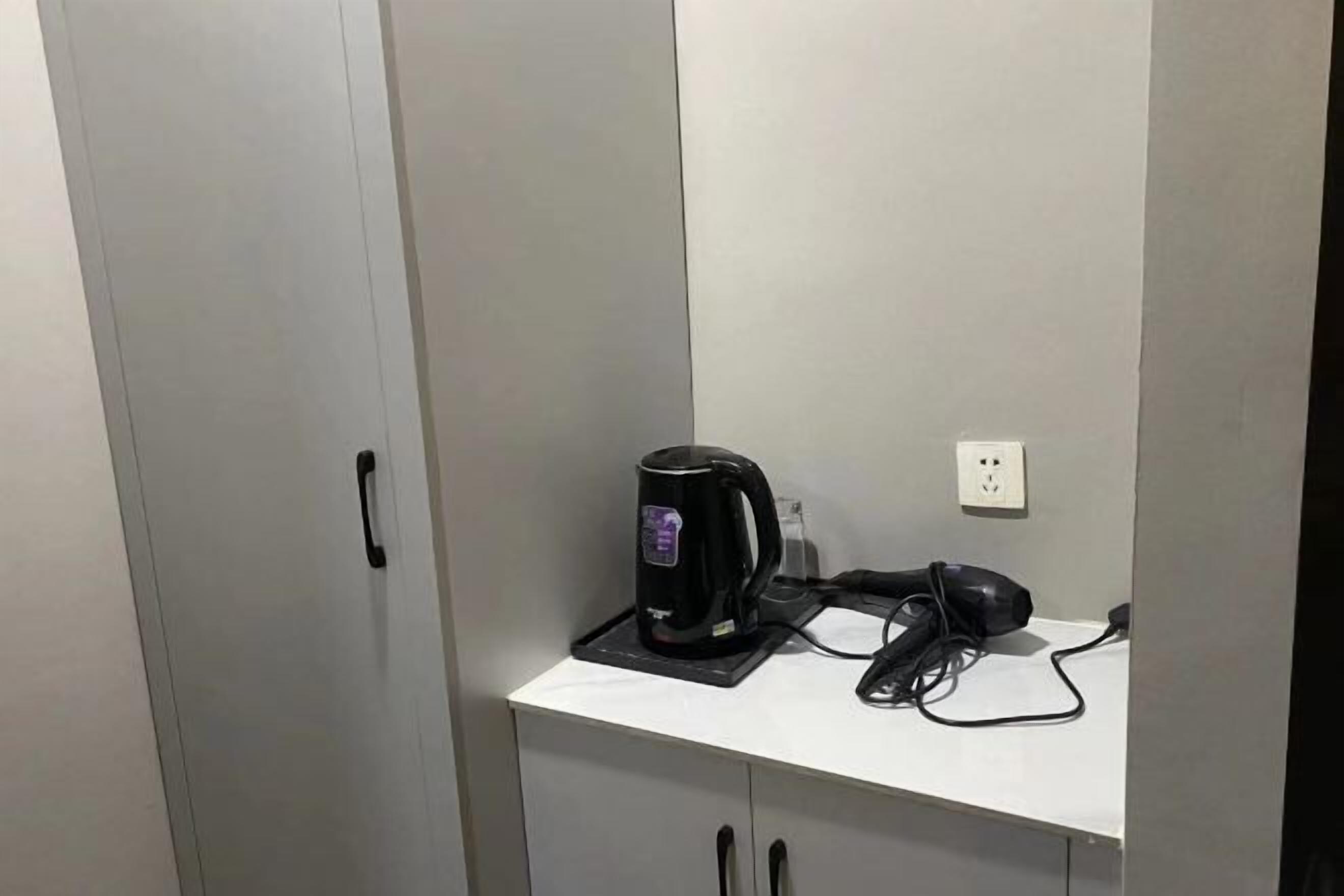 A white countertop with a black coffee maker and a hairdryer plugged in.