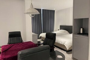 A hotel room with a bed, two chairs, a desk, a coffee machine, and a large window with curtains. - Chenxin Business Hotel (Taizhou)