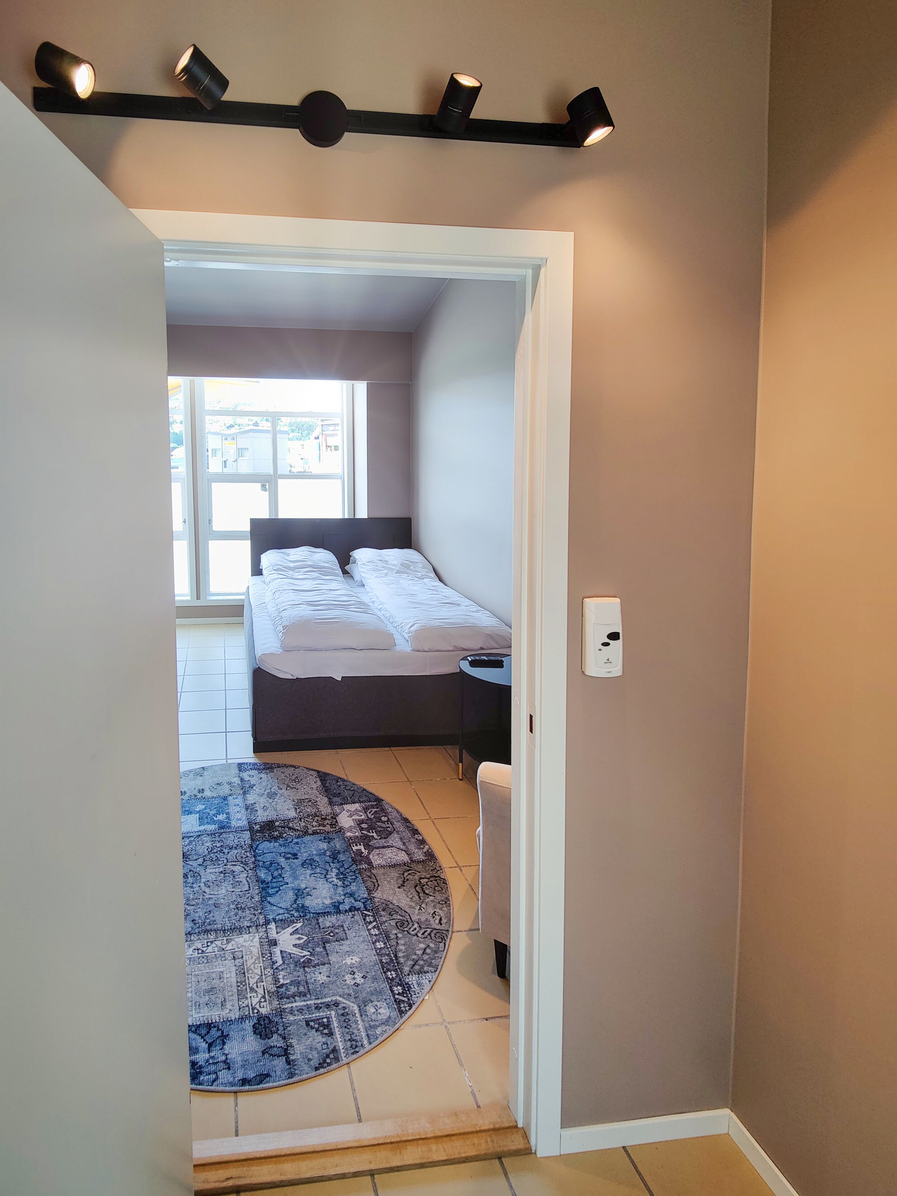 Un dormitorio con cama, alfombra y ventana.